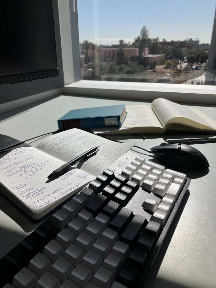 Books, handwritten notes, and a keyboard on a writer’s desk